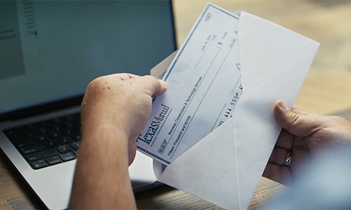 Mano sacando un cheque de dividendos de un sobre.