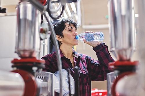 Woman drinking water in factory